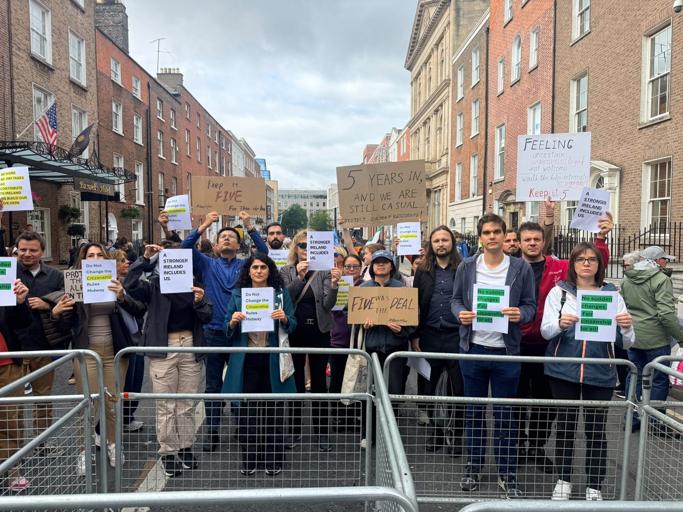 Protesters behind barriers on Kildare Street holding signs reading ‘Five was the deal’ and ‘Do not change the citizenship rules midway’