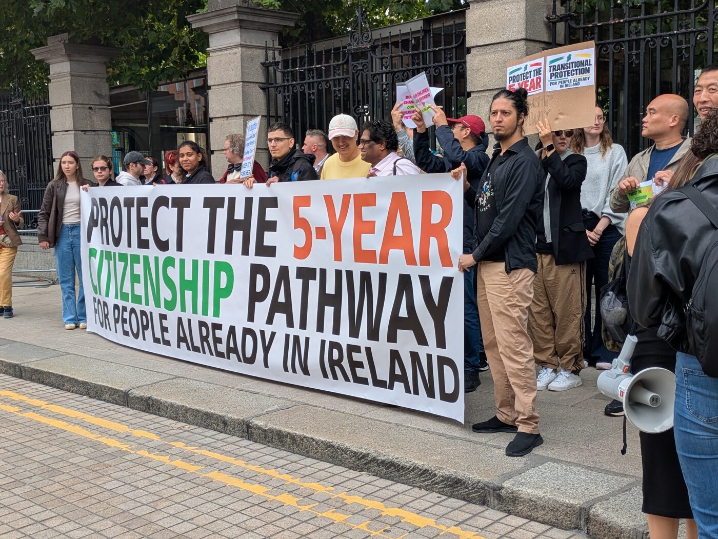 The banner ‘Protect the 5-year citizenship pathway for people already in Ireland’ at the gates of Leinster House on 24 September